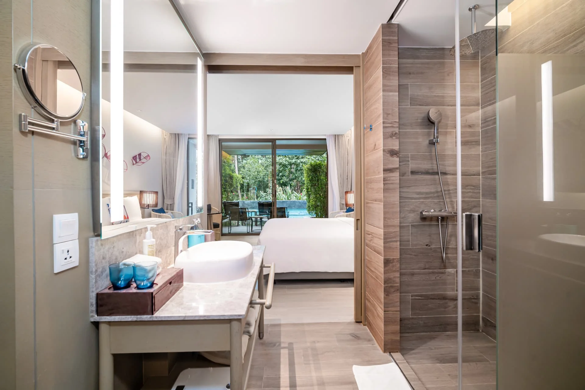 AVANI+ KAO LAK — Bathroom vanity and glass shower beside a garden window