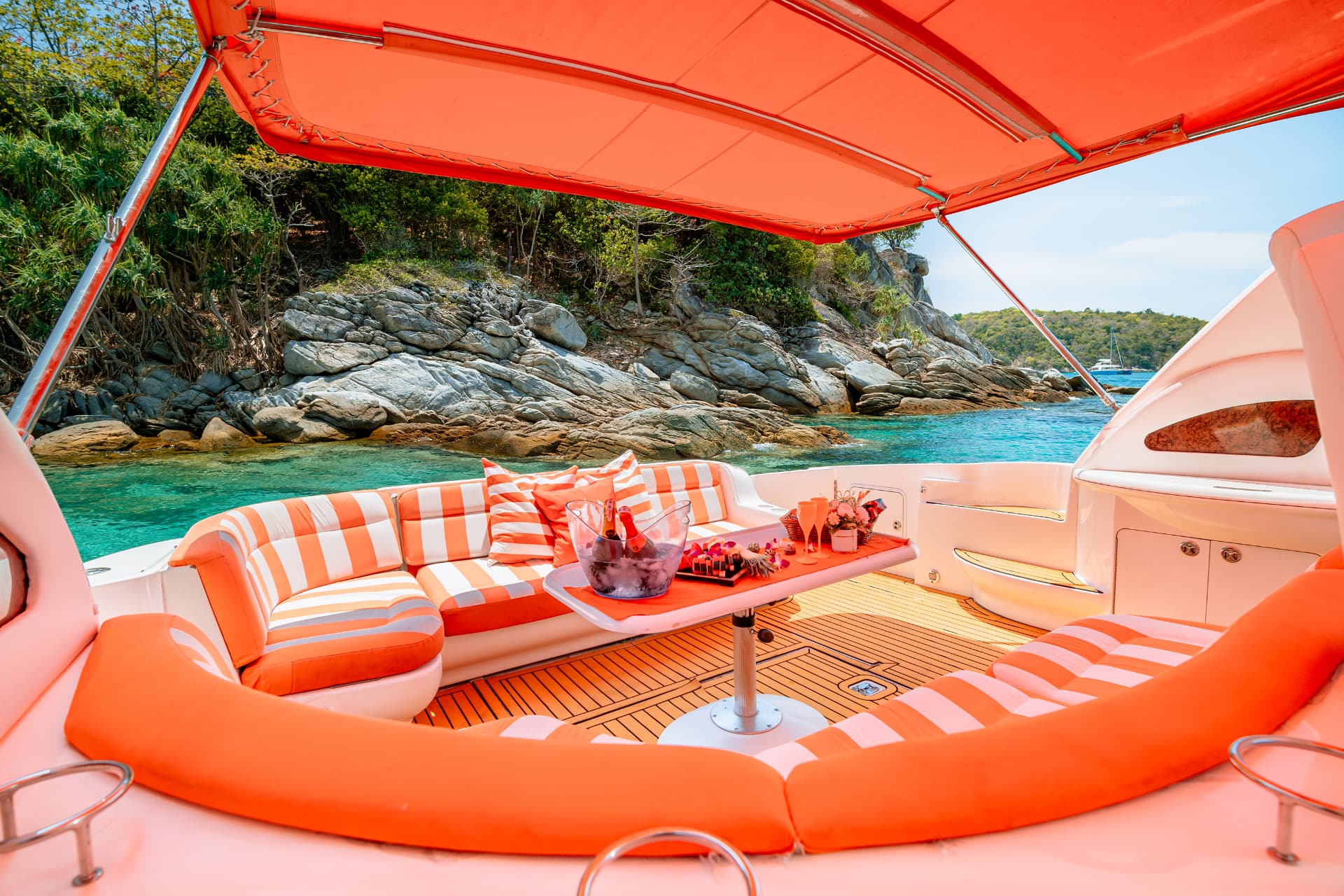 Once Yachting — covered cockpit lounge with striped seating, a set table and a view over turquoise water