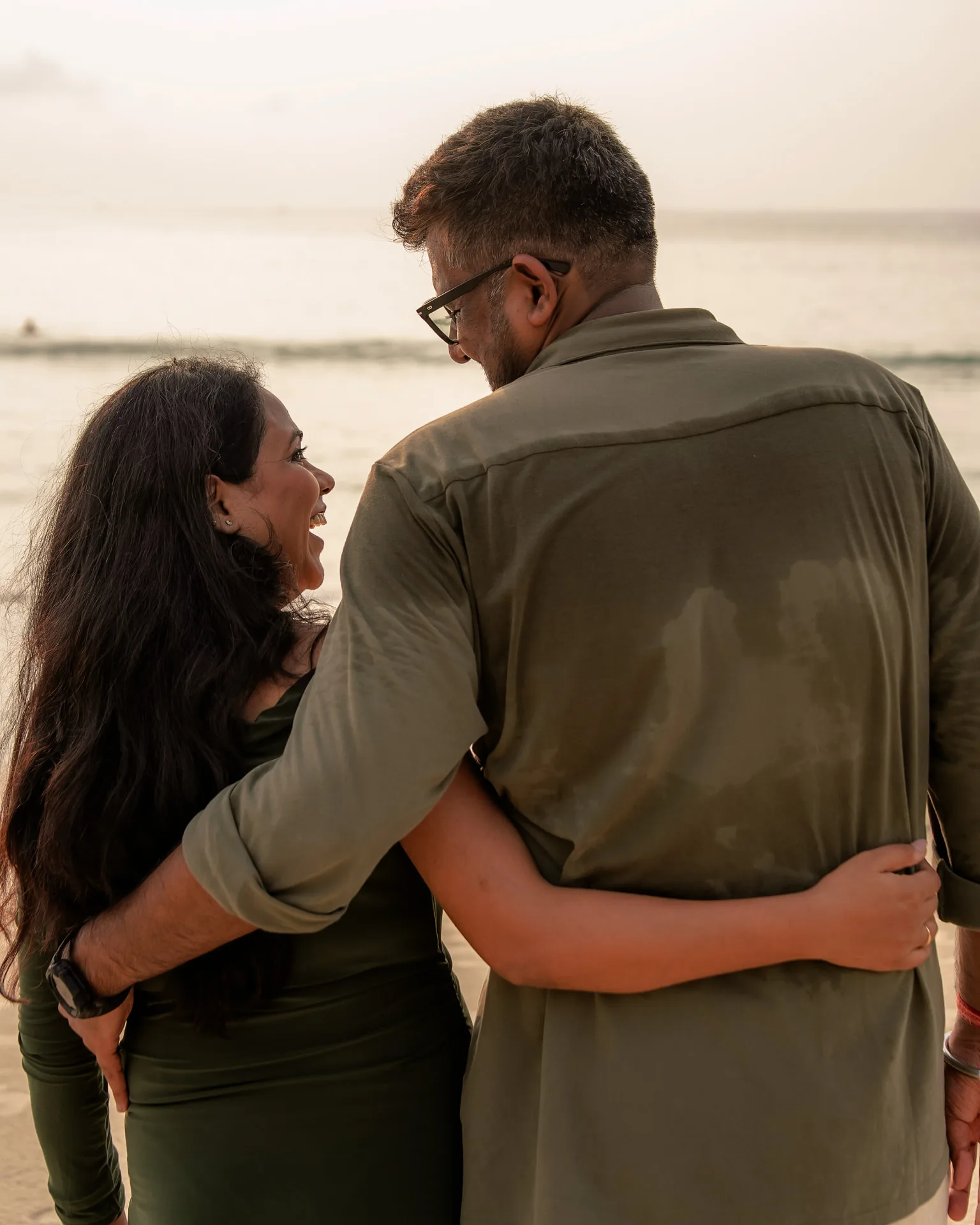 Couple embracing on the beach at sunset, seen from behind — ภาพคู่รักและช่วงเวลาร่วมกัน