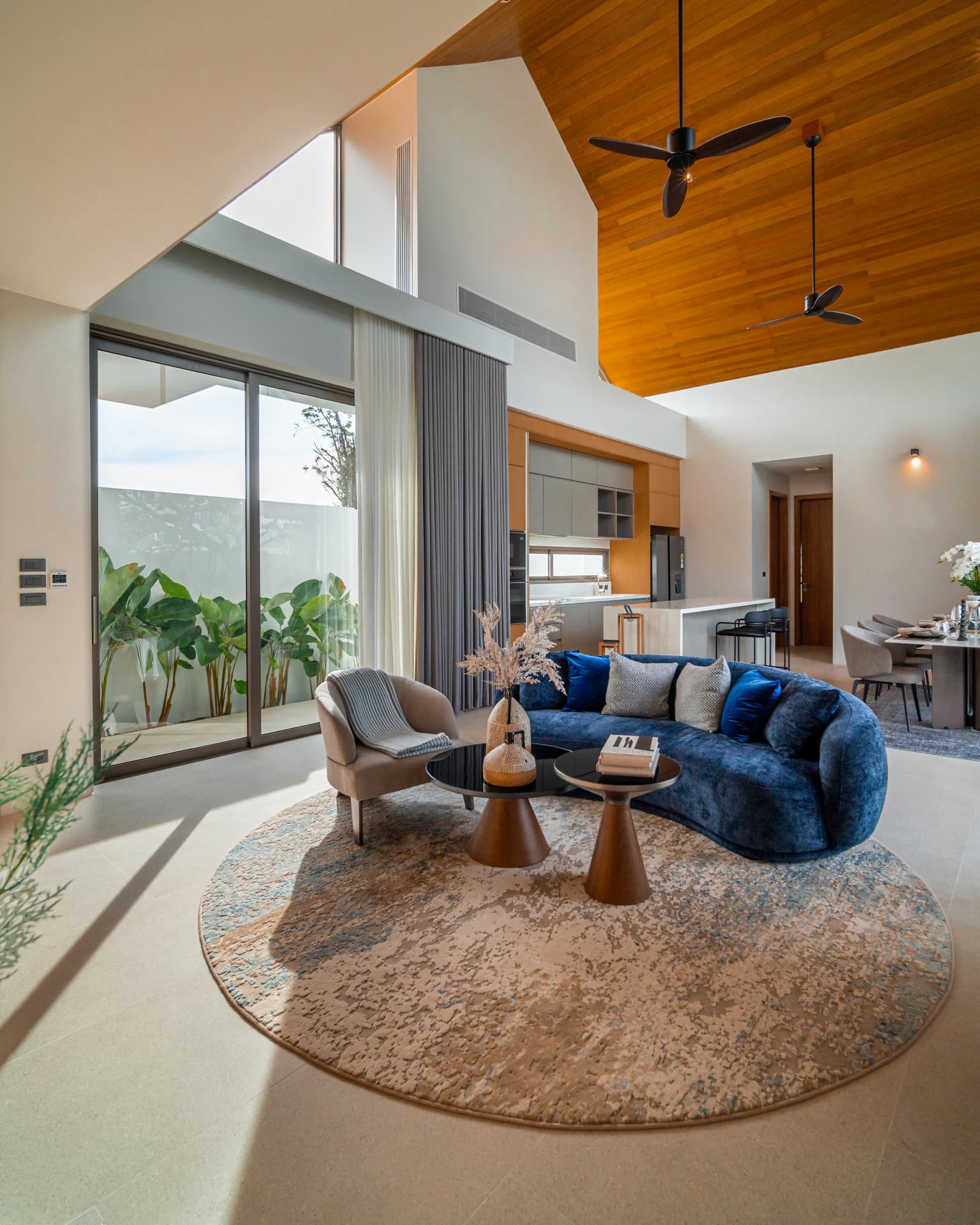 Botanica Louvre — double-height living room with a blue curved sofa