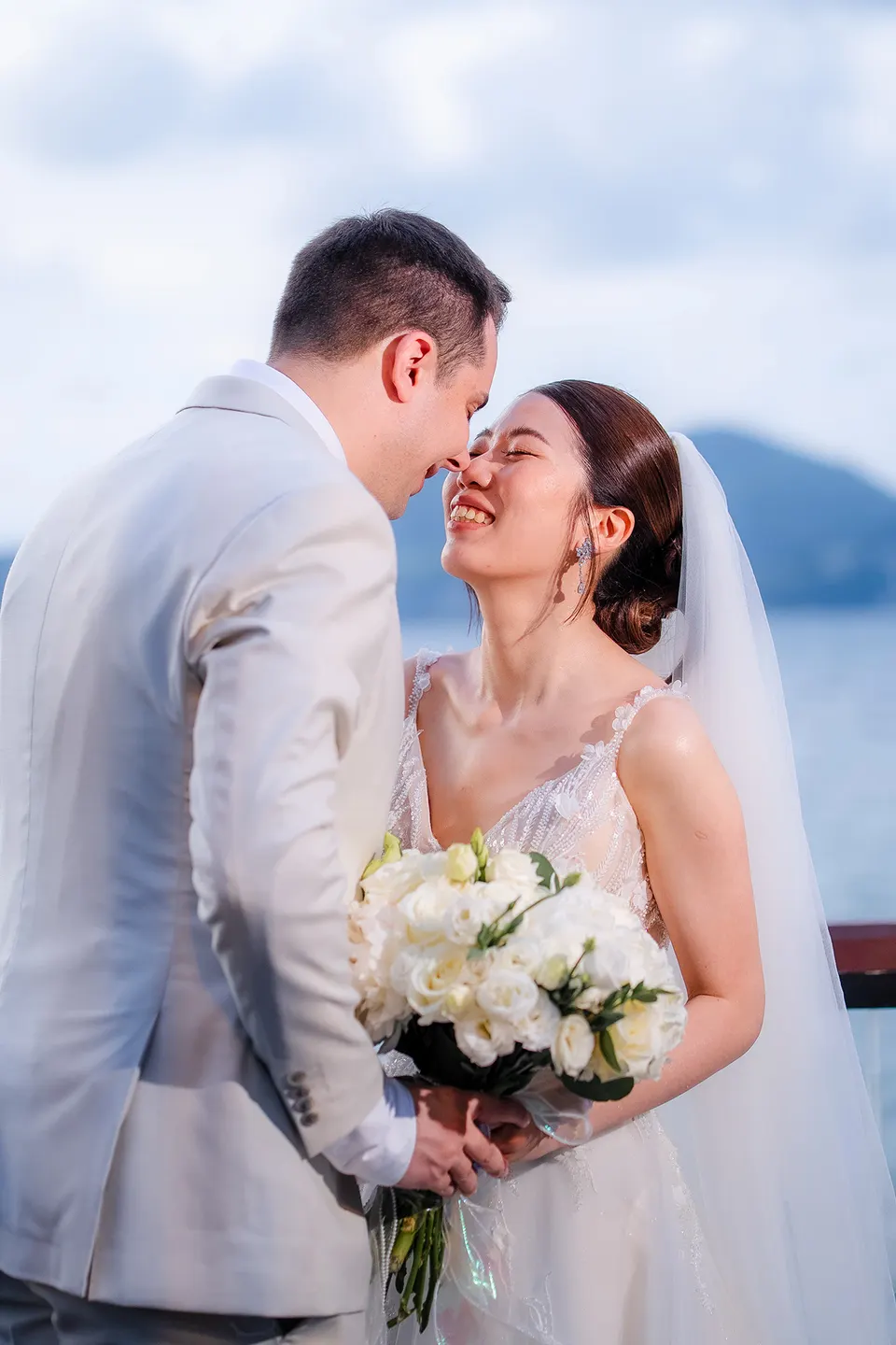 Thomas & Jane The Wedding — groom nuzzling the laughing bride's cheek as she holds a white bouquet — ภาพงานแต่งงานและคู่บ่าวสาว