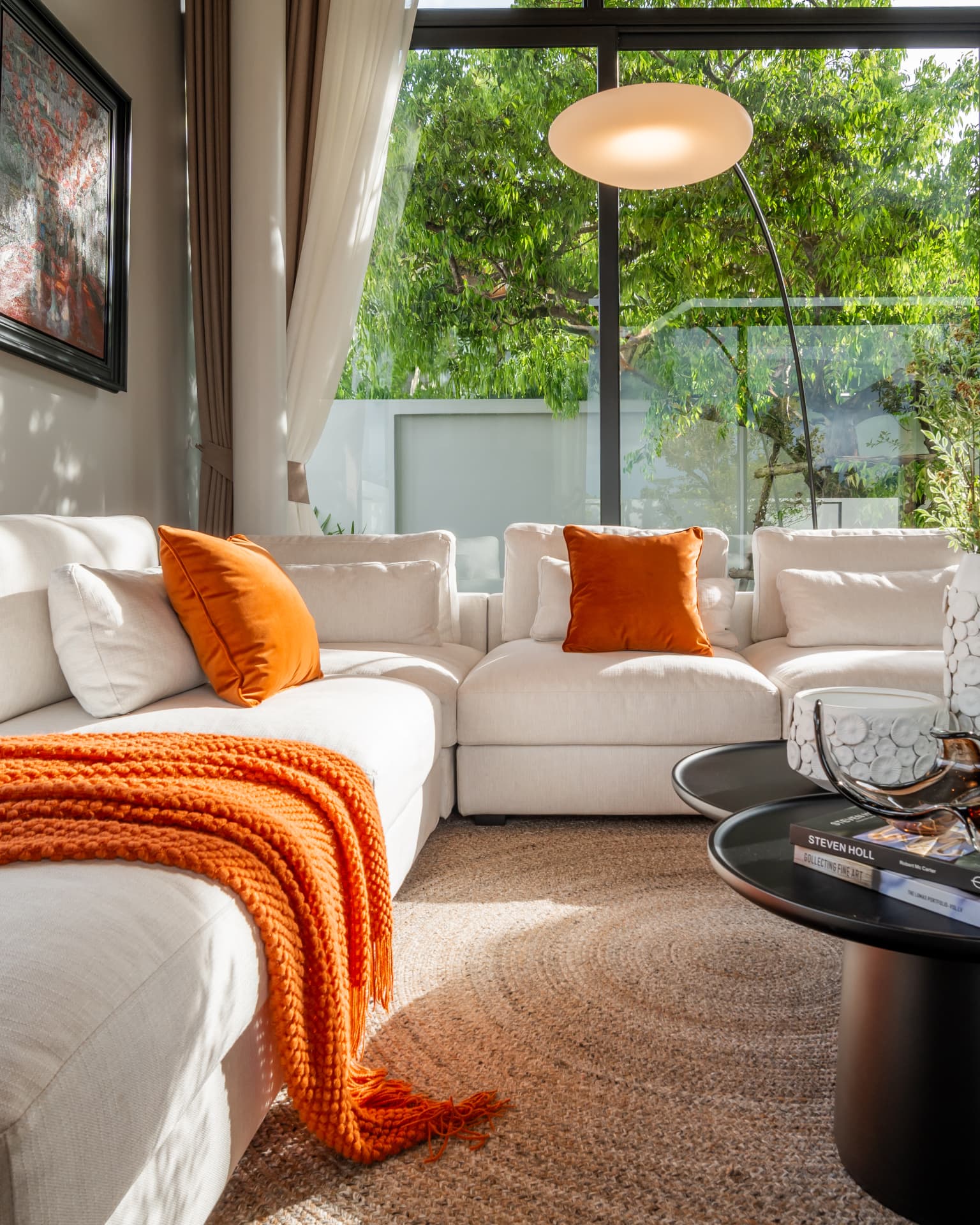 Botanica Four Seasons — living room with a cream sectional, orange cushions and a woven rug in daylight