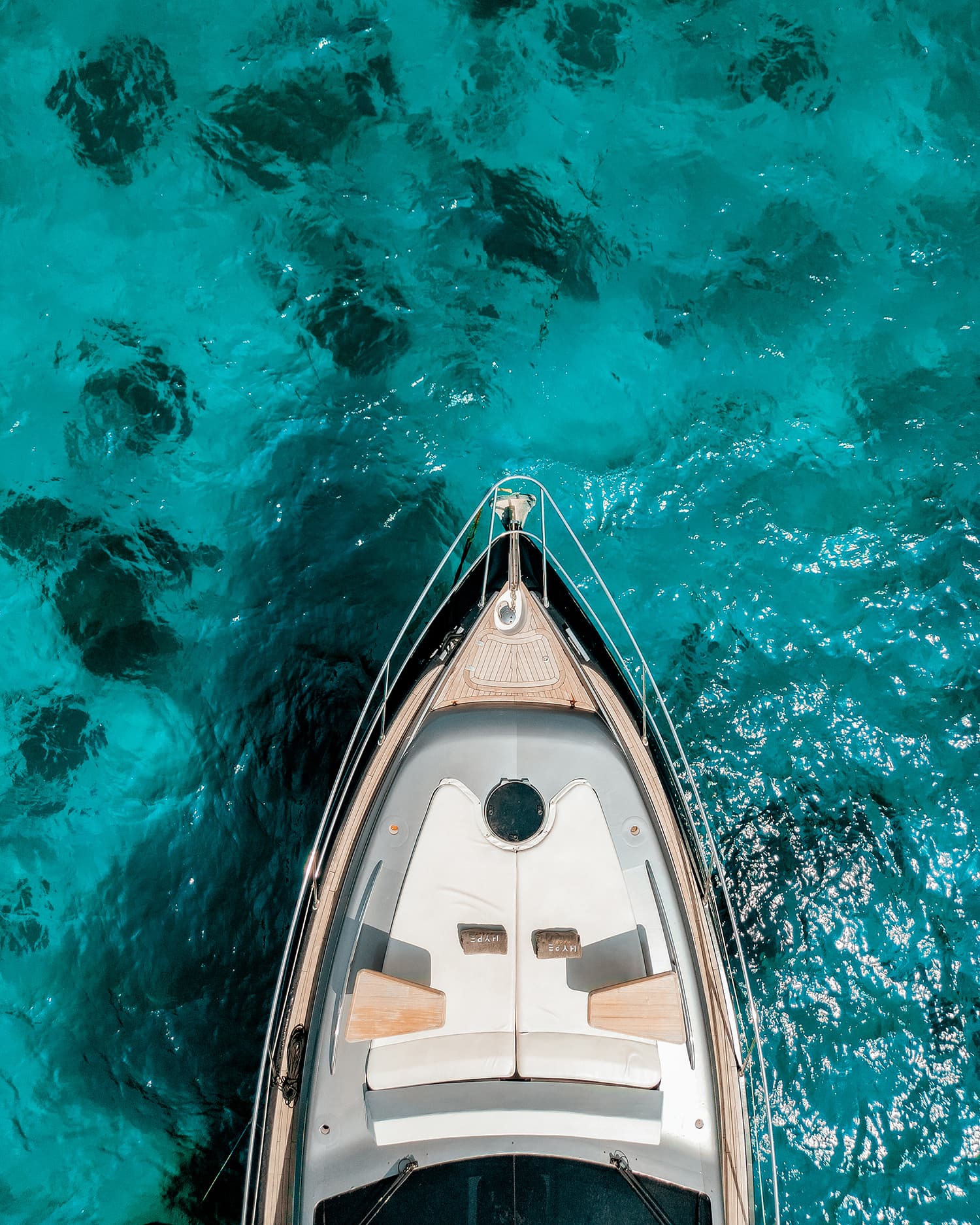 Hype Yacht — top-down view of the bow sunpad over turquoise water with HYPE cushions