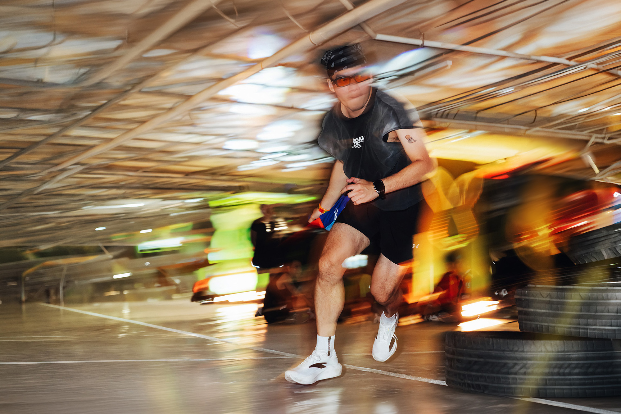 Central Phuket Beyond Move — runner sprinting toward the camera through a car park course, tyres stacked along the track, motion streaks behind him