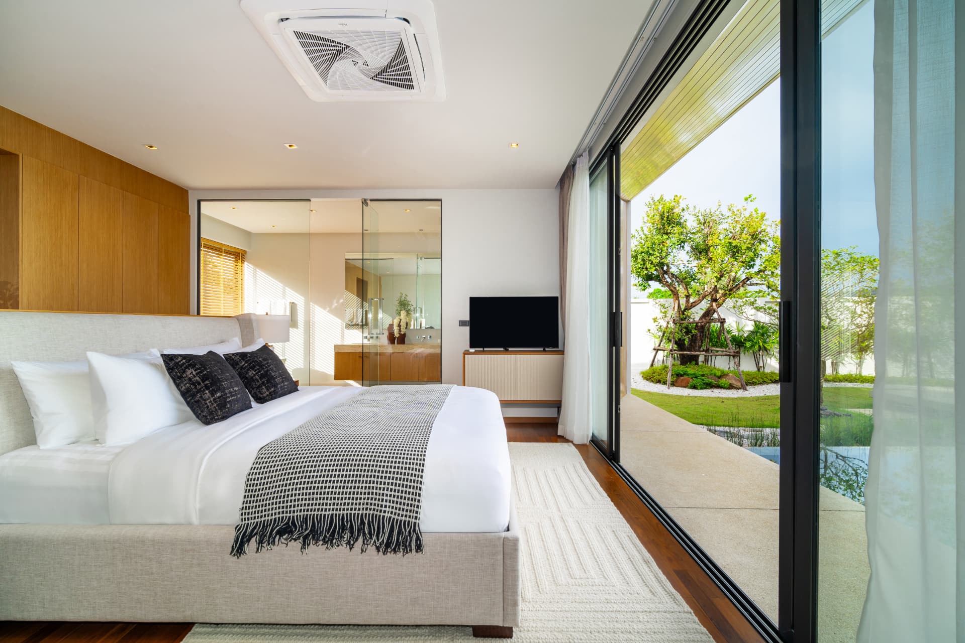 Botanica Four Seasons — bright bedroom with white bedding opening to a garden courtyard