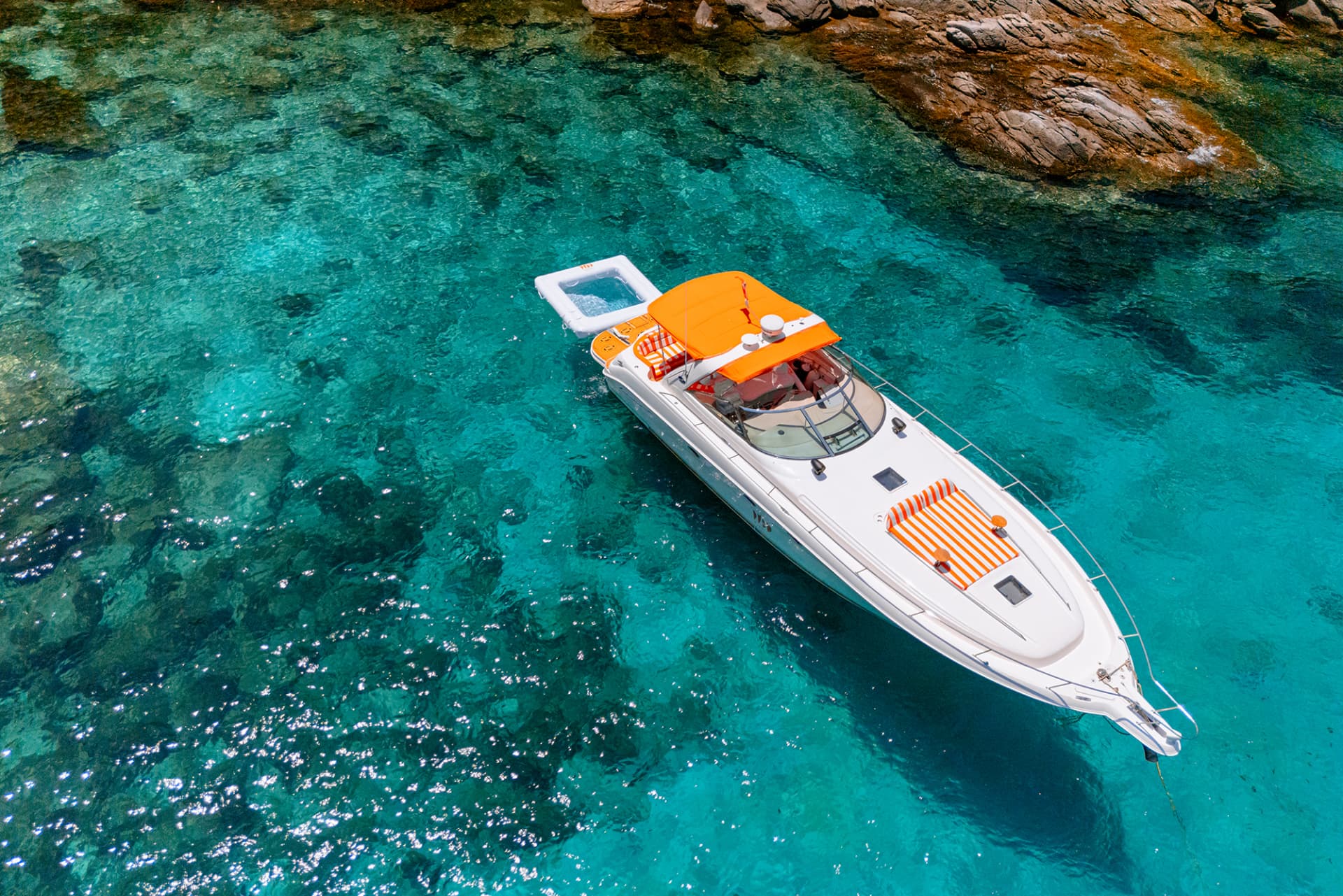 Once Yachting — aerial view of the motor yacht with orange canopies anchored in a turquoise cove
