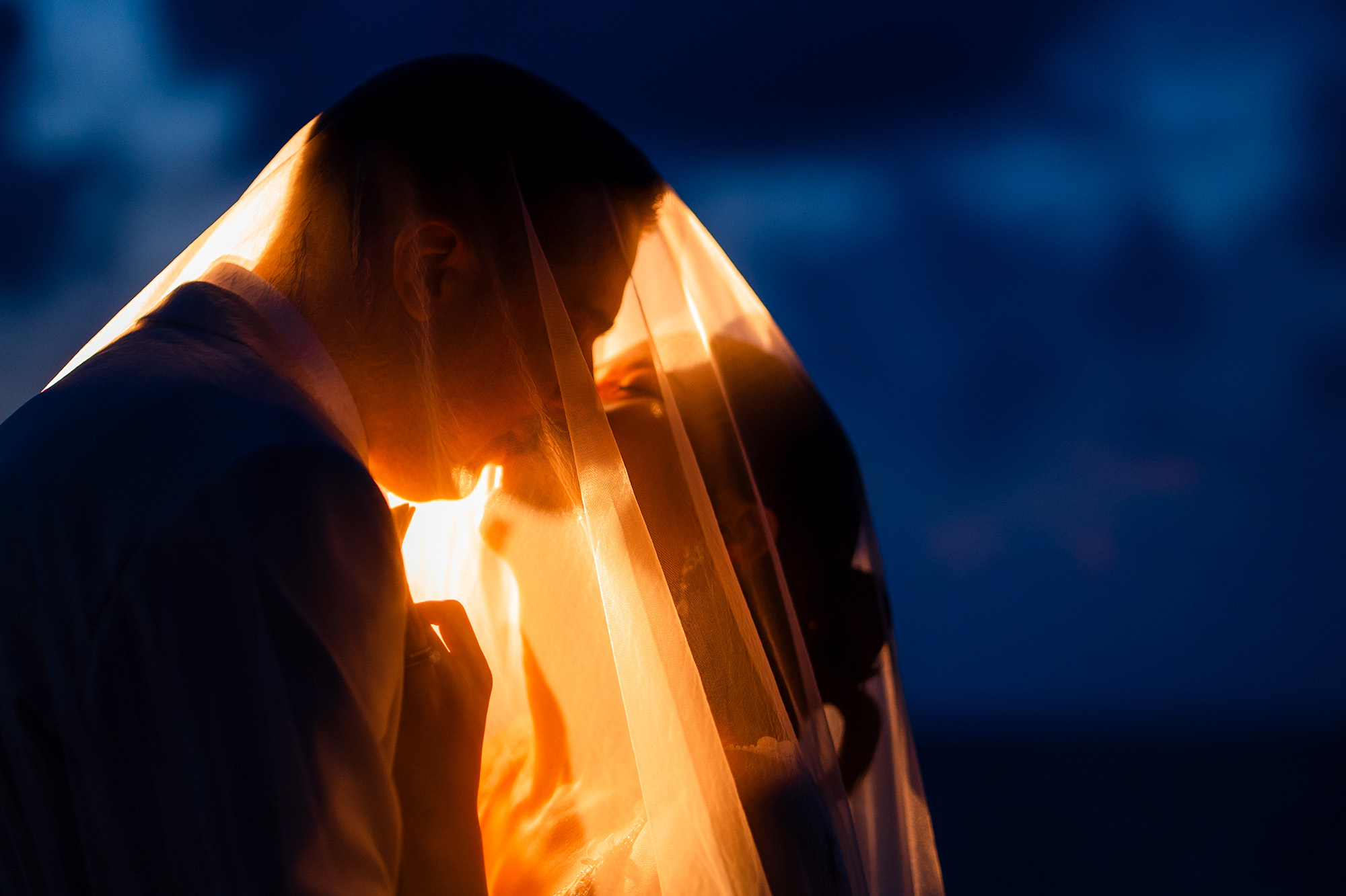 Thomas & Jane The Wedding — silhouetted couple kissing beneath a golden veil at sunset