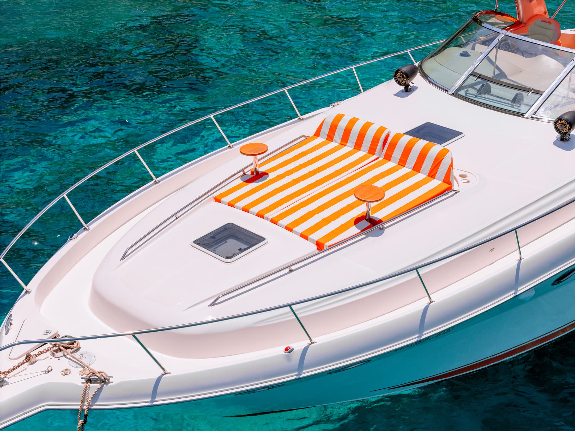 Once Yachting — bow deck with twin orange-and-white striped sun pads and wooden cup holders
