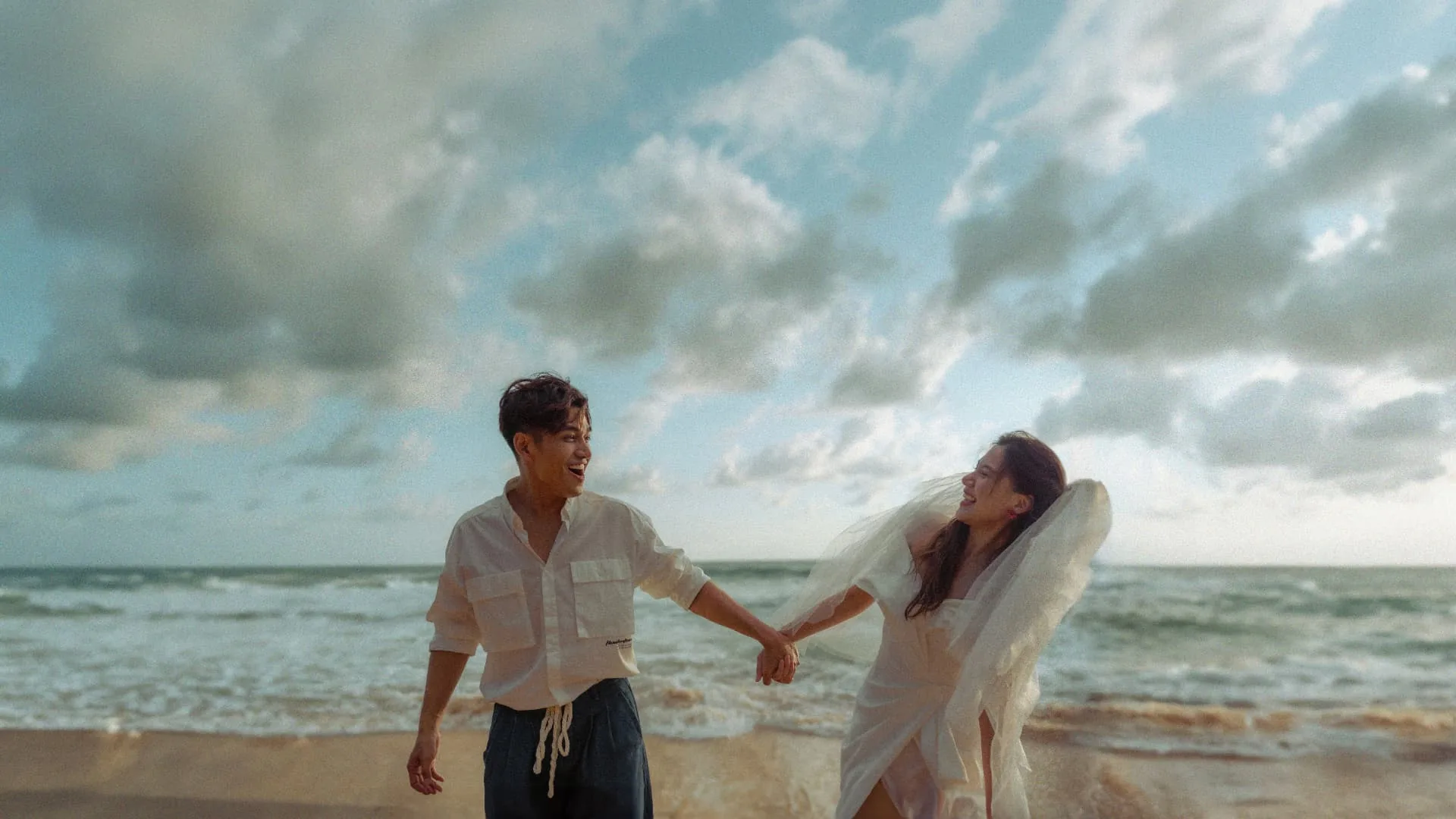 Couple holding hands by the waves — ภาพคู่รักและช่วงเวลาร่วมกัน