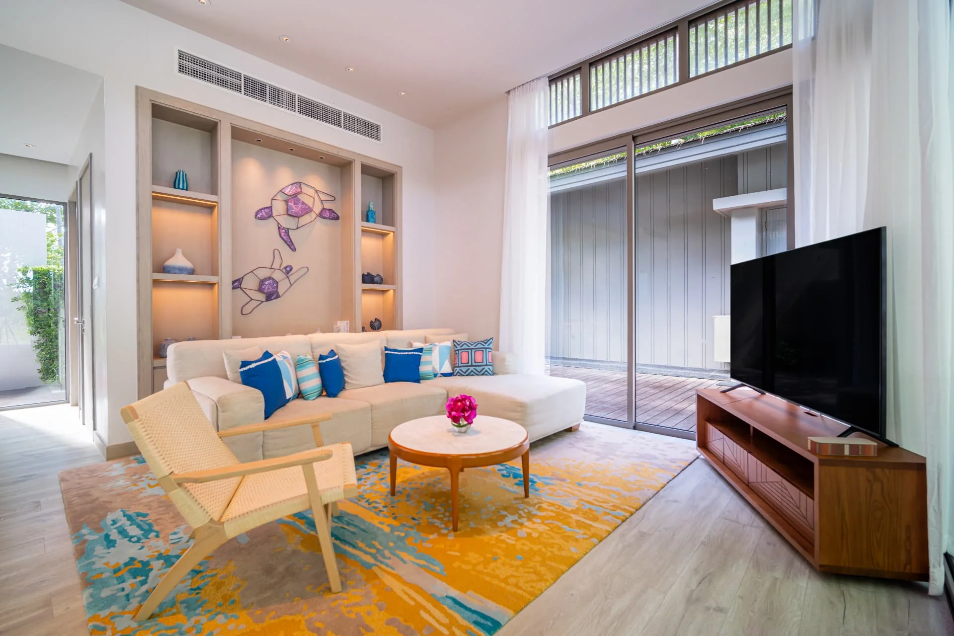 AVANI+ KAO LAK — Living room with blue cushions, timber furniture and tall windows
