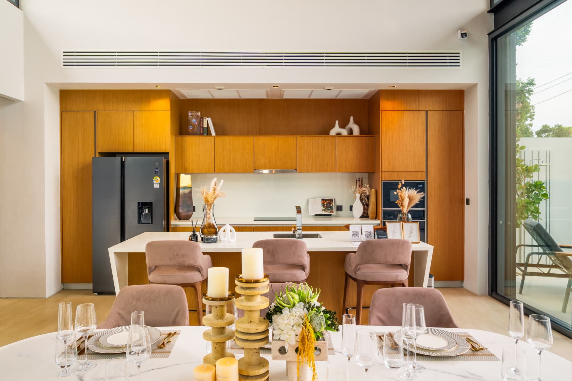 Botanica Foresta II — kitchen and dining room with a set marble table, an island with stools and warm wood cabinetry