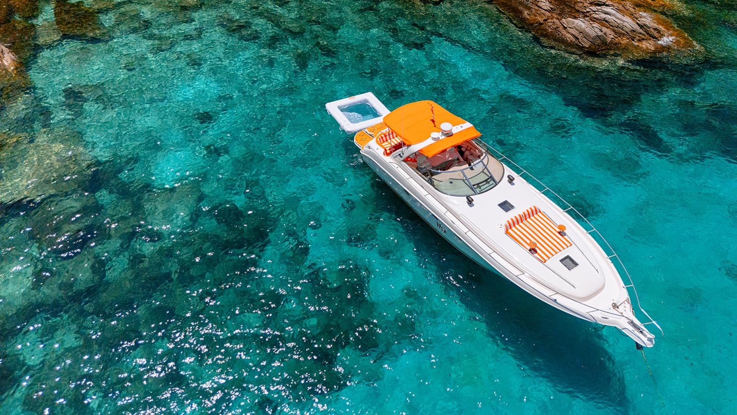ONCE YACHTING — motor yacht anchored in a turquoise cove, seen from above