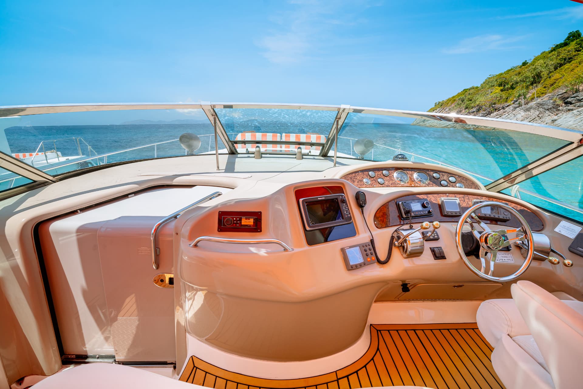 Once Yachting — helm station with steering wheel and navigation instruments looking out to sea