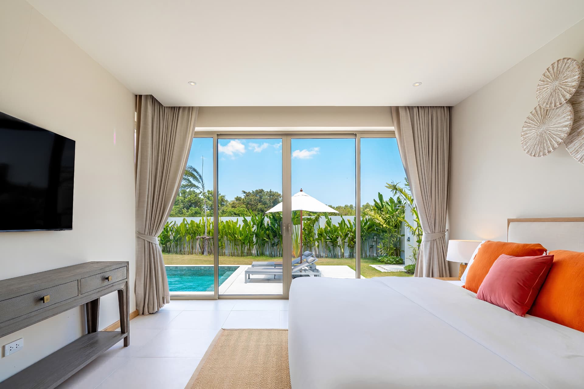 Trichada Villas — bedroom with orange cushions opening onto the pool terrace