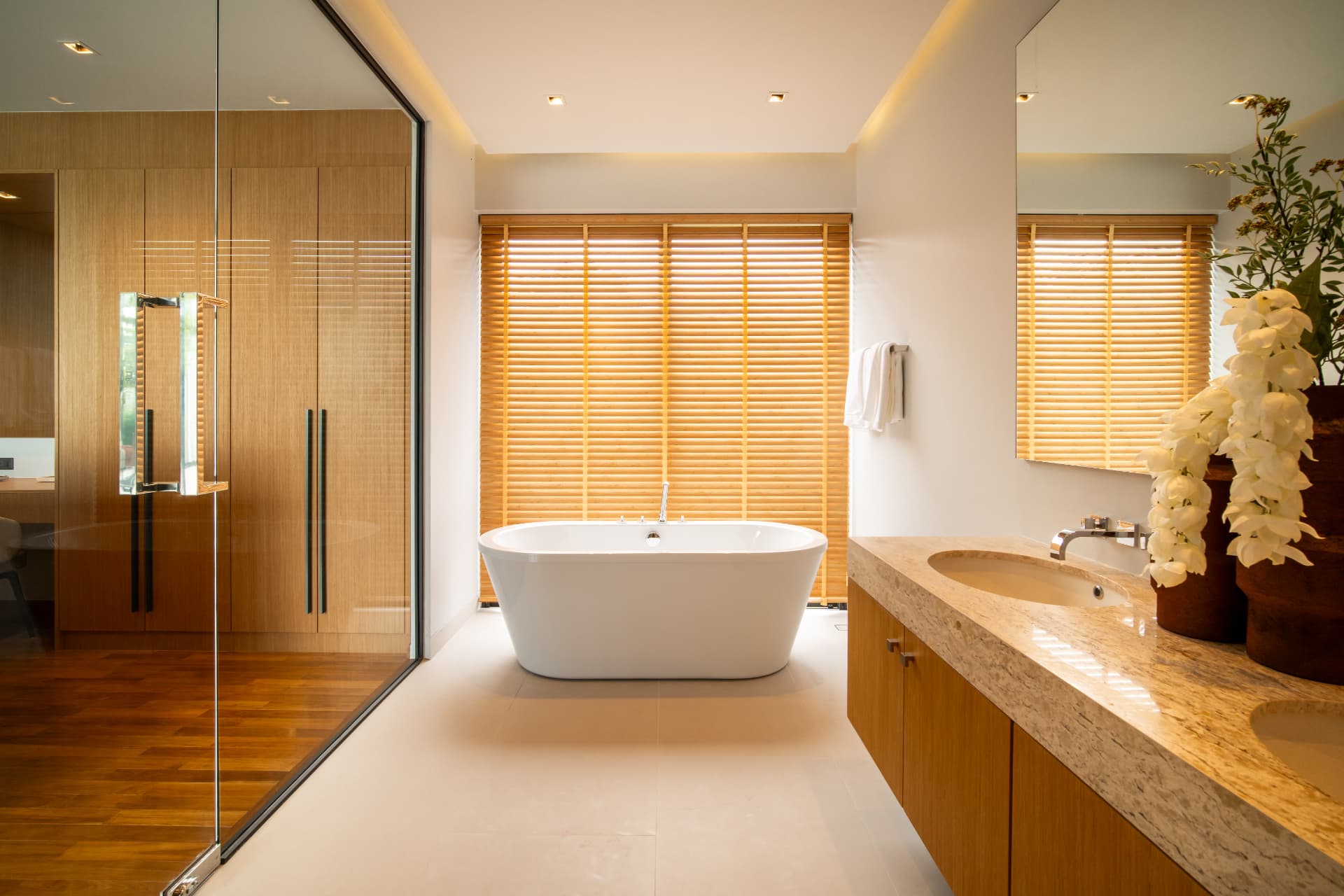 Botanica Four Seasons — bathroom with a freestanding tub and travertine vanity behind timber blinds