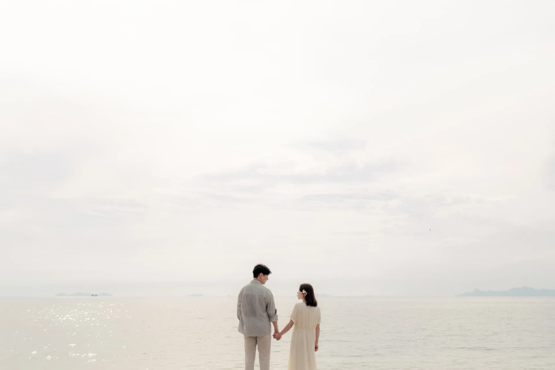 Couple standing hand in hand at the water's edge — ภาพคู่รักและช่วงเวลาร่วมกัน