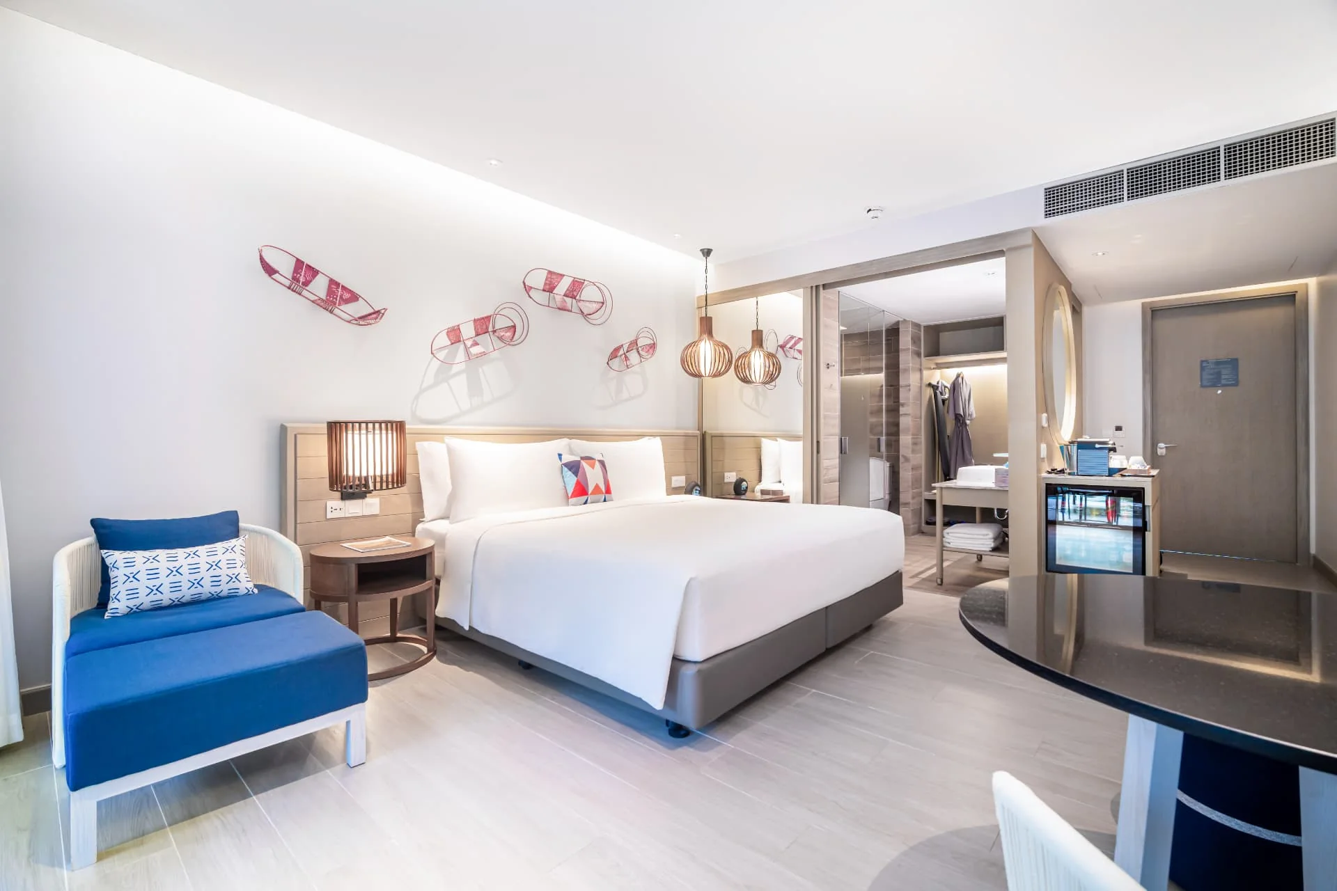 AVANI+ KAO LAK — Guest bedroom with a blue sofa and white bedding