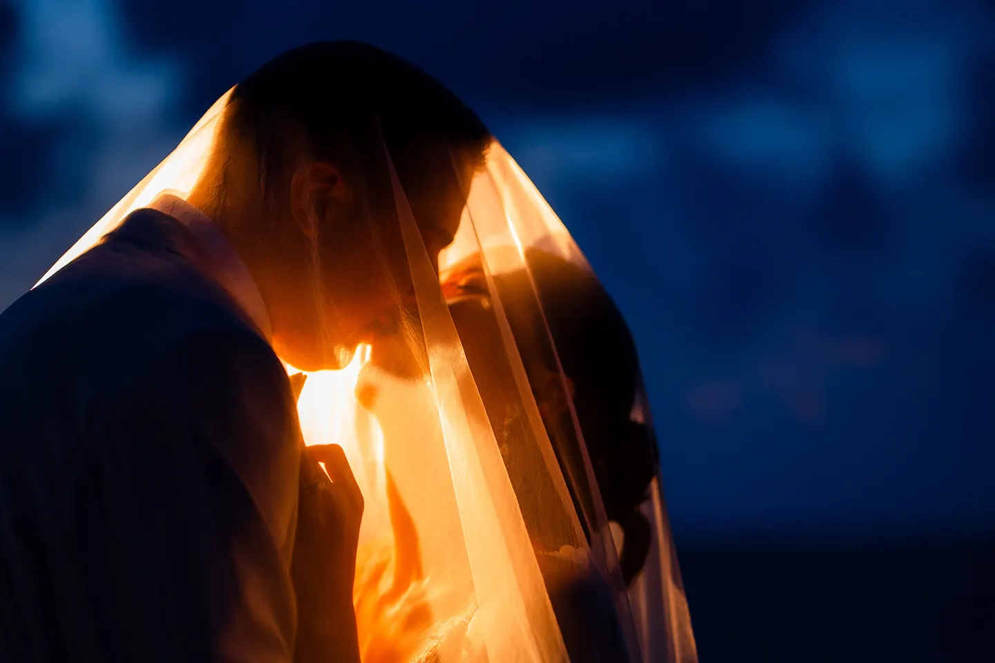 Thomas & Jane The Wedding — silhouetted couple kissing beneath a golden veil at sunset — ภาพงานแต่งงานและคู่บ่าวสาว