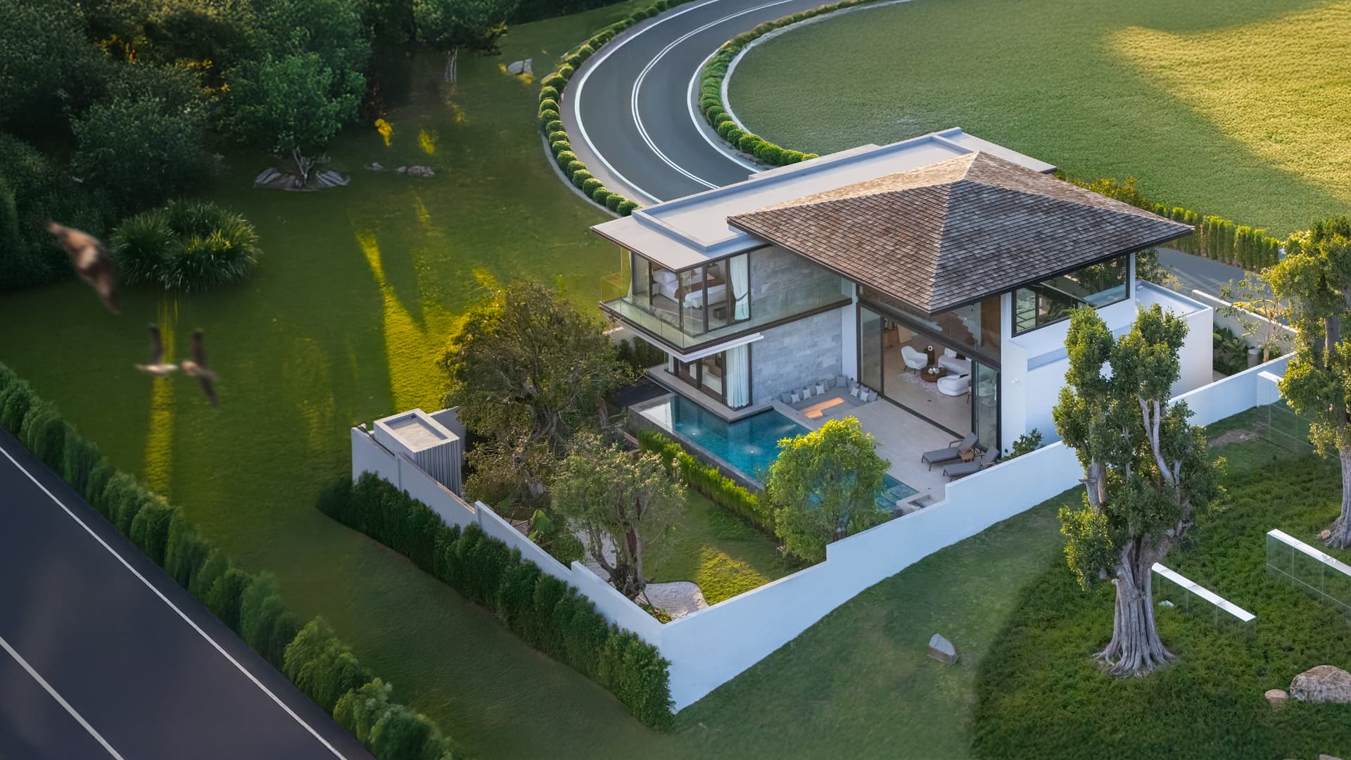 Botanica Foresta II — aerial view of a two-storey villa with a pool beside a winding road