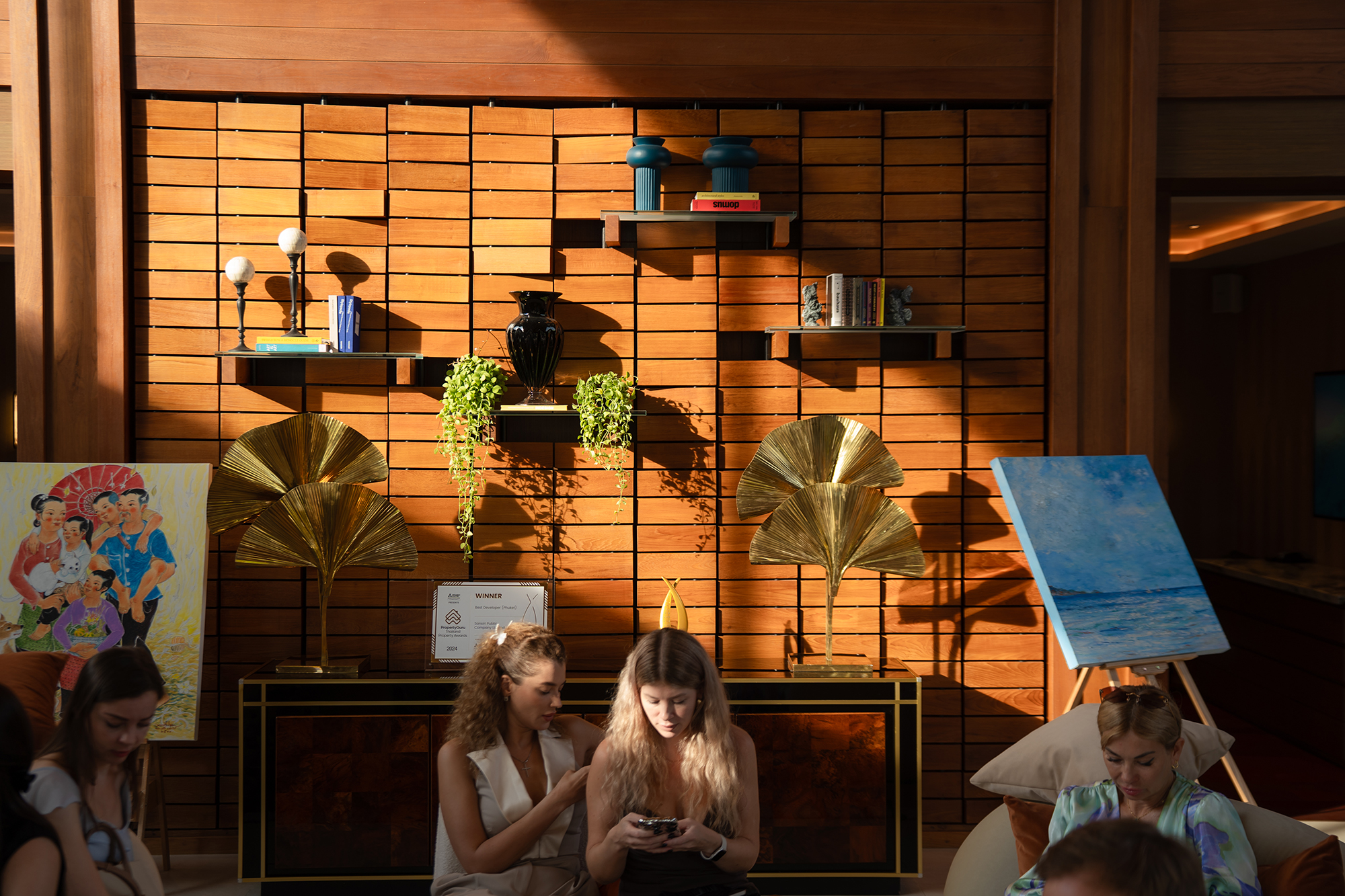 Sansiri New Year Dinner — guests relaxing in a warm timber lounge with golden afternoon light across the wall